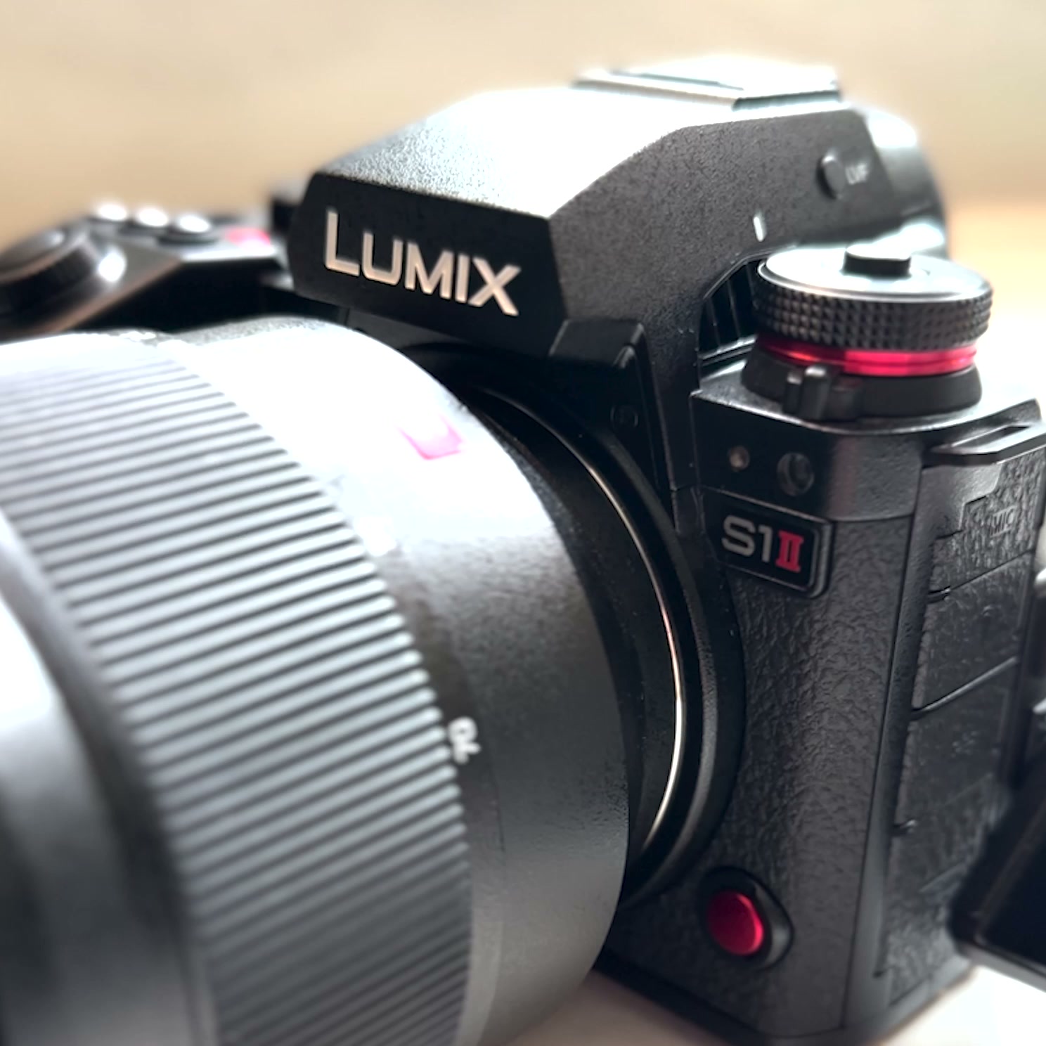 Close on a Lumix S1 II body and lens, the red record button in the foreground.