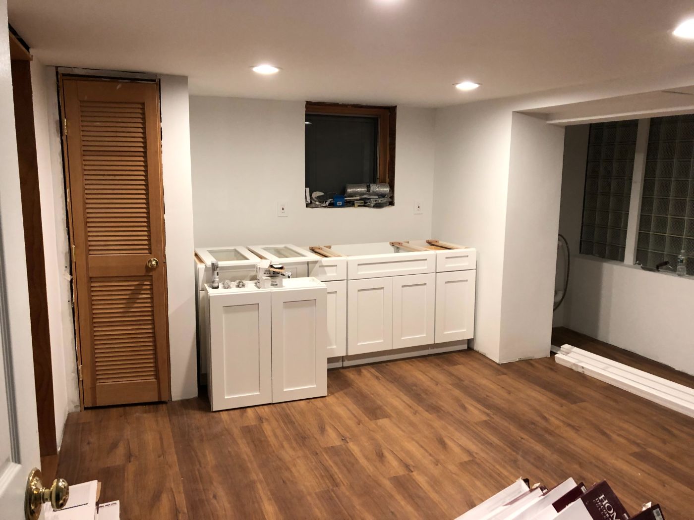 Kitchenette cabinets going in, floor down.