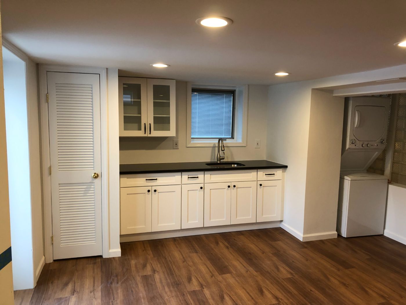 The finished studio: white cabinets, black counter, laundry in the alcove.