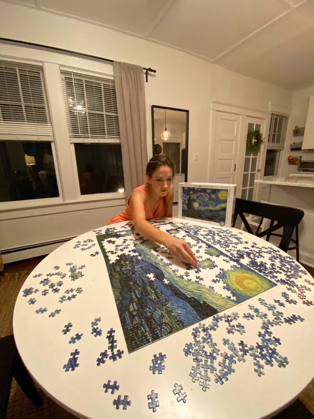 Steph working on a Starry Night jigsaw at the round dining table, late evening.