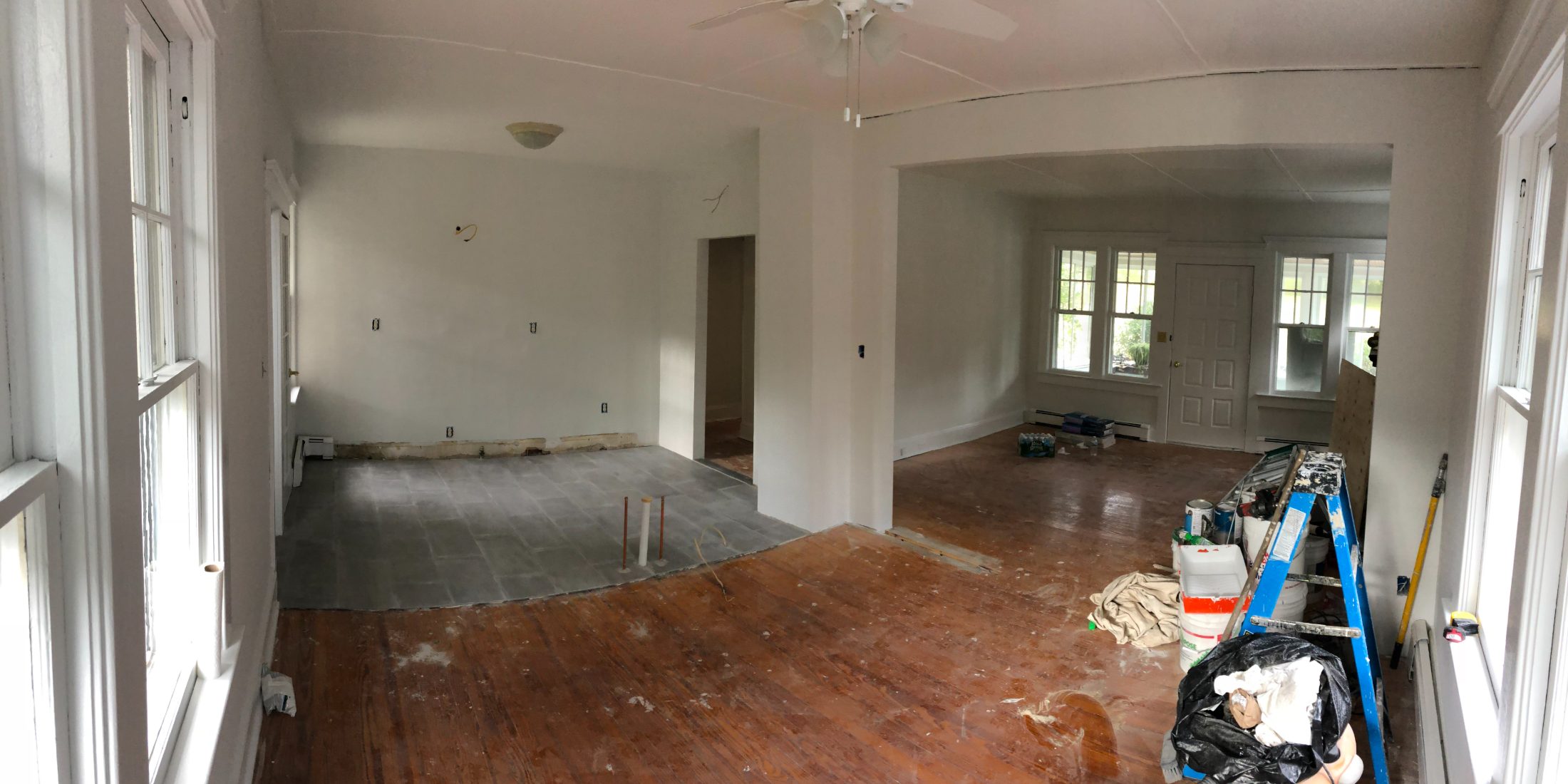 The same view stripped and patched: bare subfloor, tile underlayment, empty rooms.