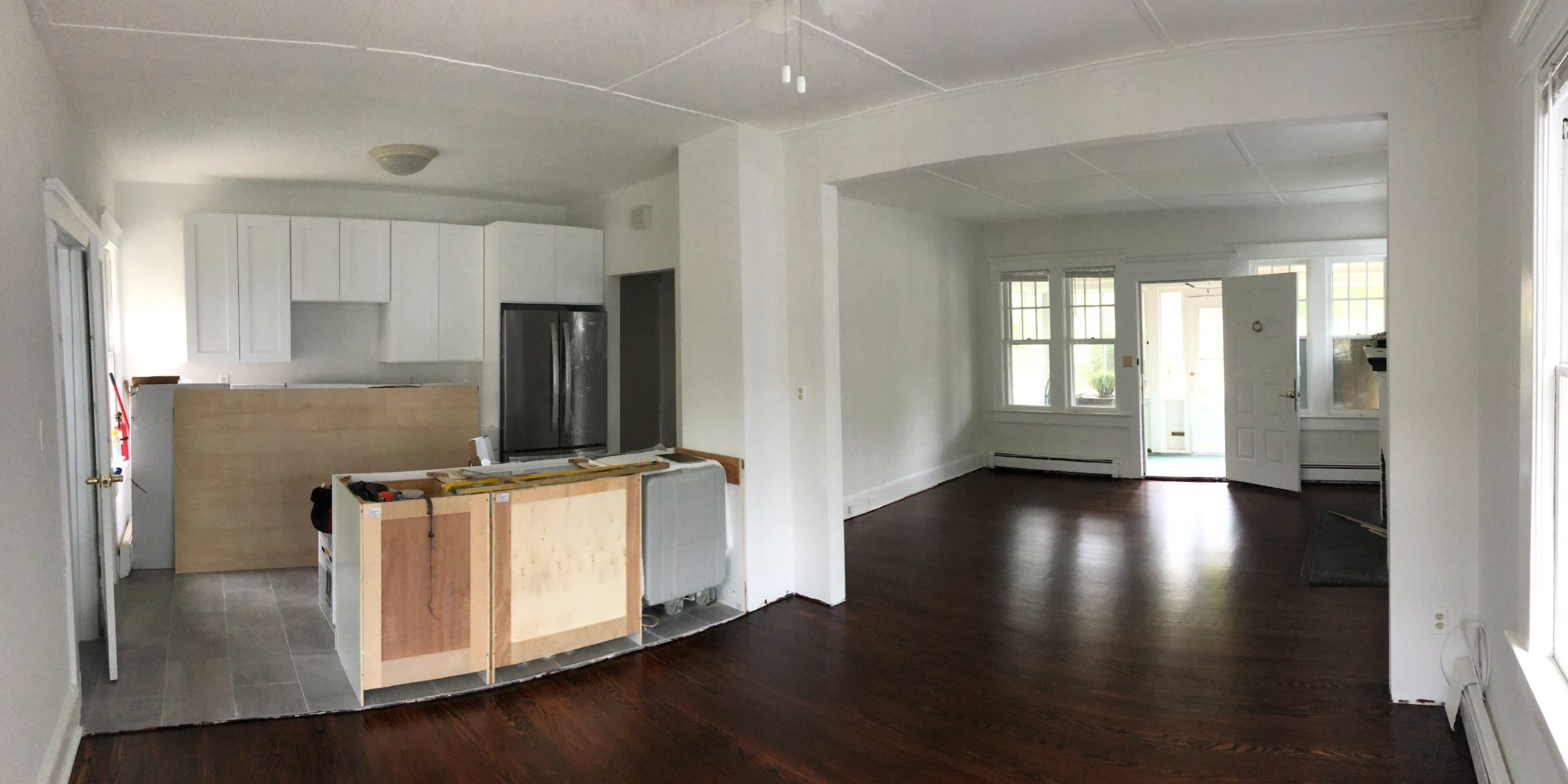 The same view with cabinets installed, the island framed in plywood, floors refinished dark.