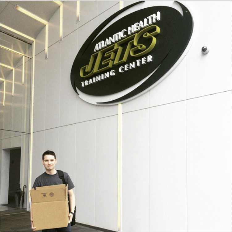 Justin on his last day at the New York Jets, standing with packed boxes from his editing desk.