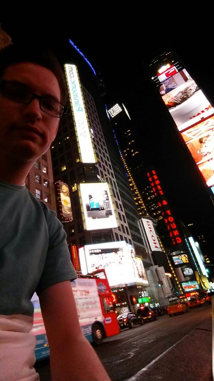 Justin Herrera in Times Square at night, Panasonic billboard behind him.
