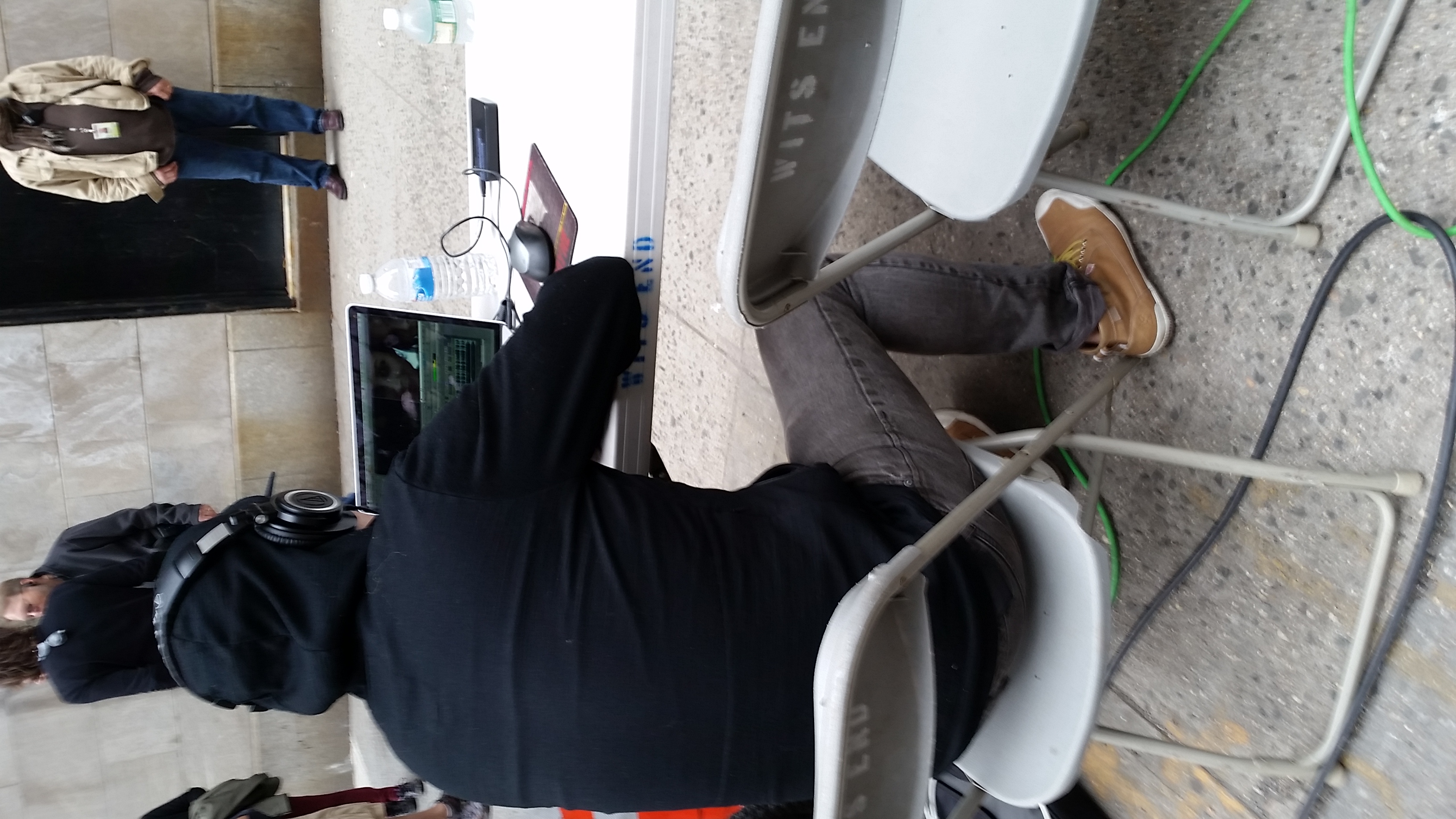 Joseph Kahn in a hooded jacket and headphones, reviewing Justin's cut at the laptop on set.
