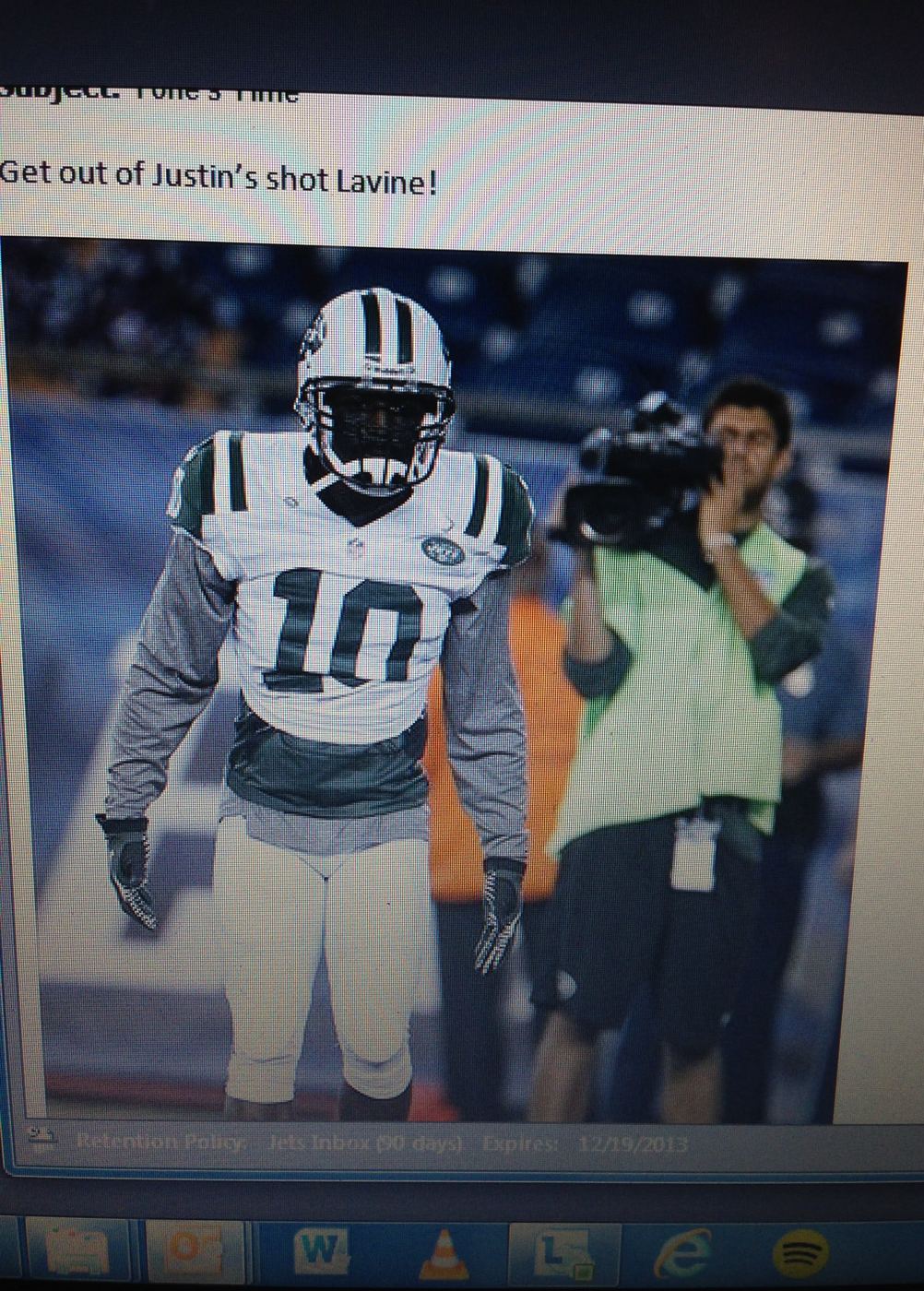A photograph of a computer monitor showing an internal Jets email dated December 19, 2013. Subject line: Tone's Time. Body: Get out of Justin's shot Lavine. Below it, a photo of Santonio Holmes in his number 10 jersey walking past a camera operator.