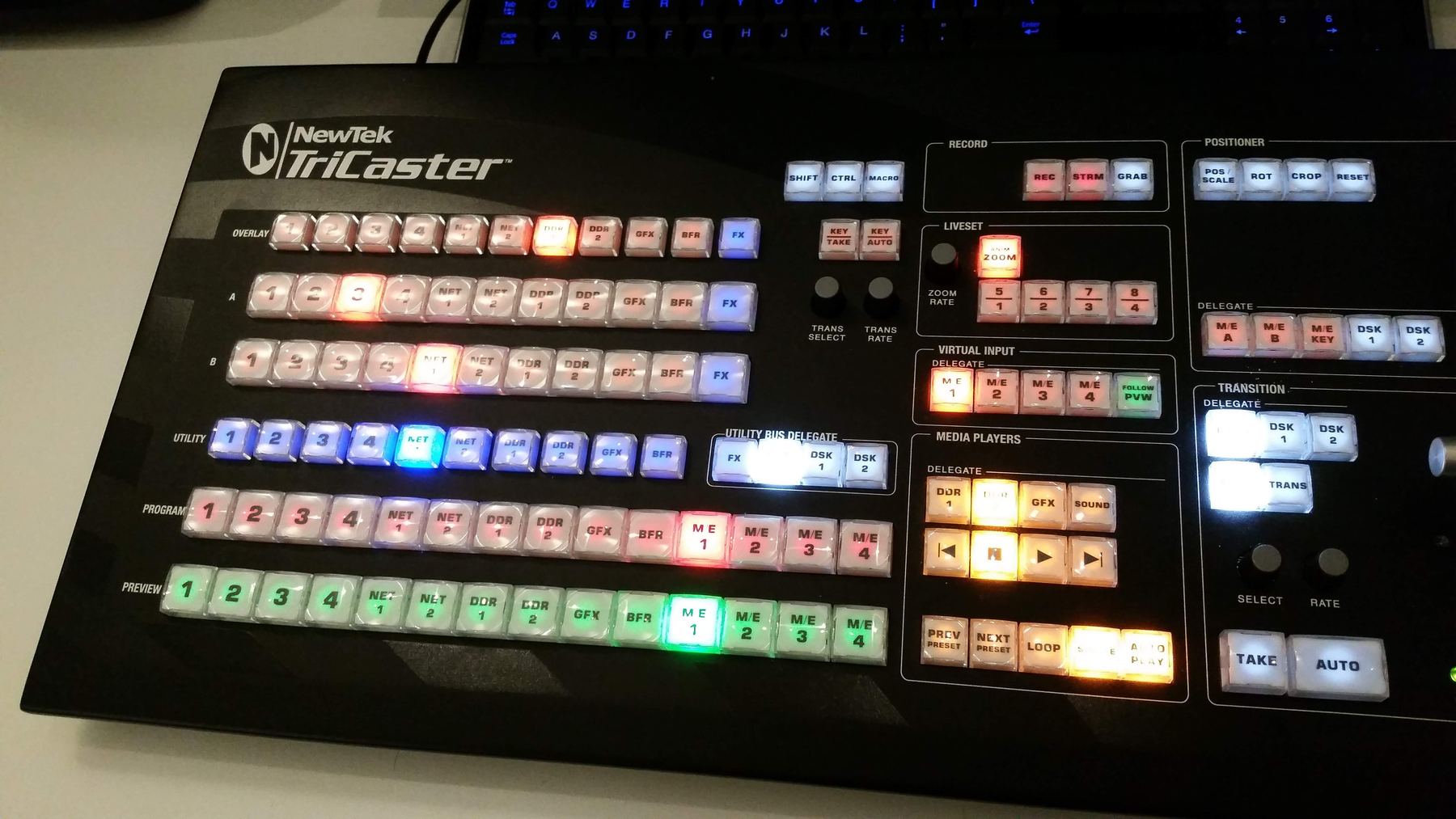 A NewTek TriCaster control surface with every button lit in red, green, blue and amber.