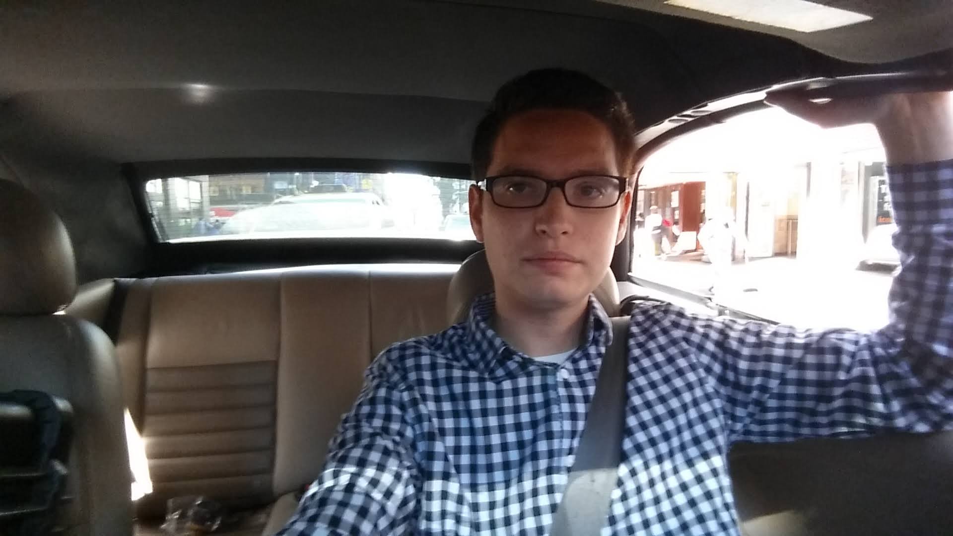 Justin in the backseat on the way to set, holding the camera up for a selfie.